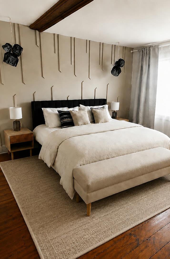 Chambre principale aux tons sable, tête de lit capitonnée noire et tapis de jute.