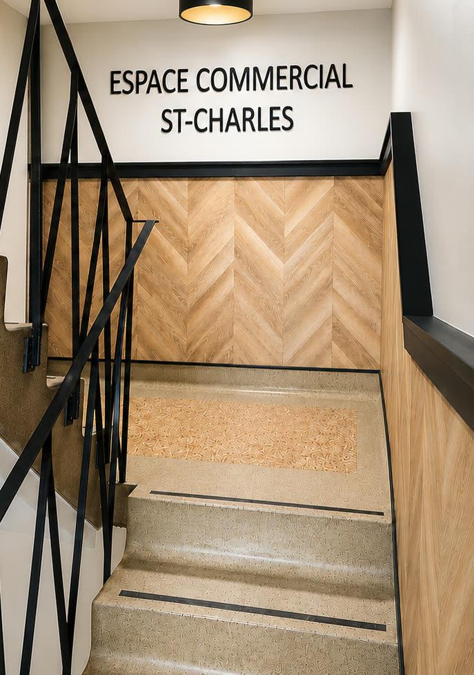 Escalier d’entrée commercial habillé de chevrons de chêne clair, avec signalétique murale « Espace Commercial St-Charles ».